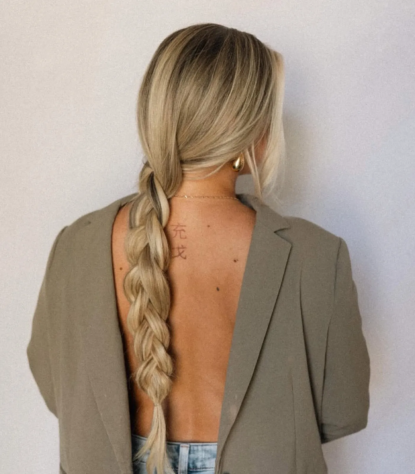Long blonde braid draped over the shoulder, back view